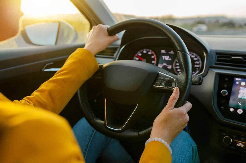 Gros plan sur les mains d'une femme en costume jaune conduisant une voiture