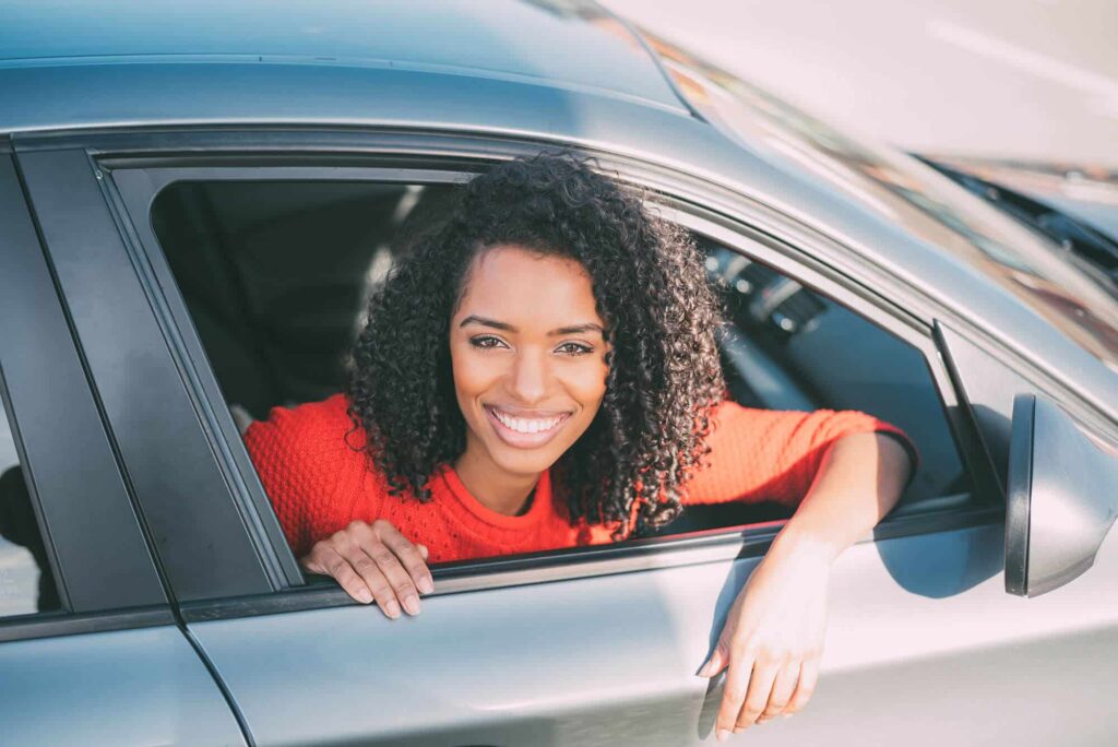 Jeune femme noire assise dans la voiture et souriant